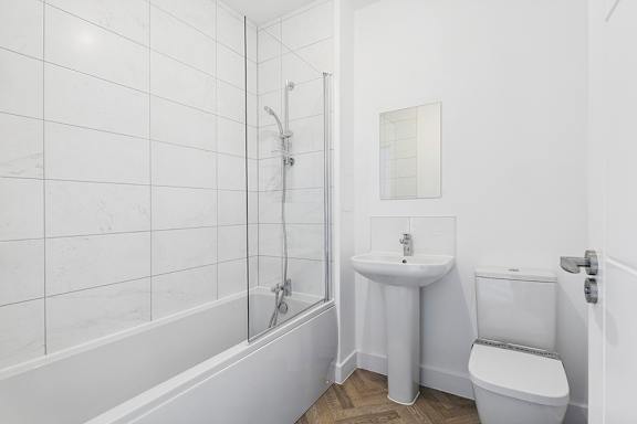 A white bathroom with a tub, toilet, and sink.