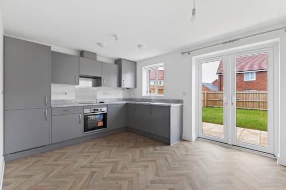 A modern kitchen with a wooden floor and a view of a backyard.
