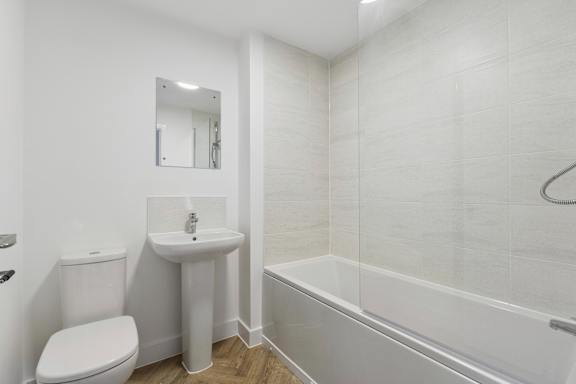 A white bathroom with a toilet, sink, and bathtub.