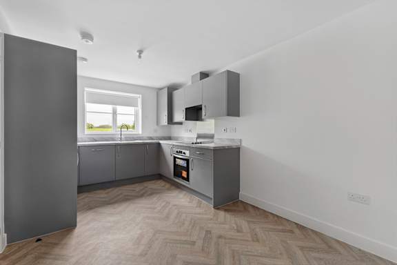 A kitchen with a refrigerator, oven, and microwave.