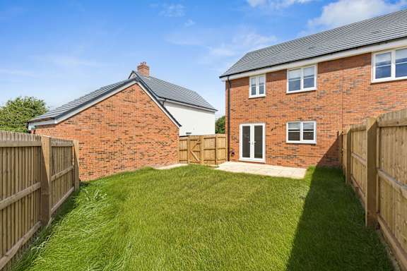 A red brick house with a white door and a small garden.