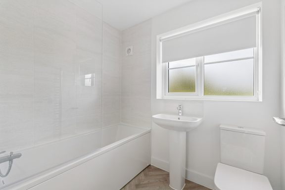 A white bathroom with a tub, sink, and toilet.