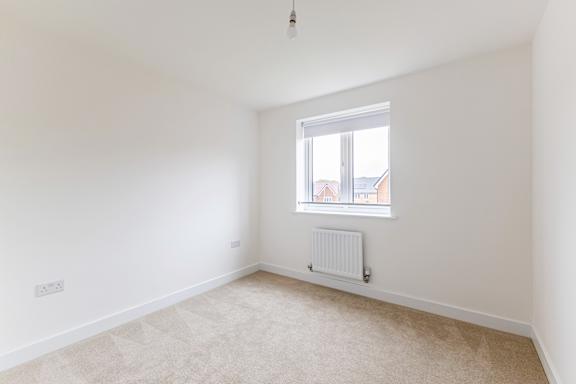 A white room with a window and a radiator on the wall.
