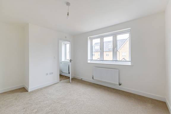 A room with a window, a radiator, and a door.