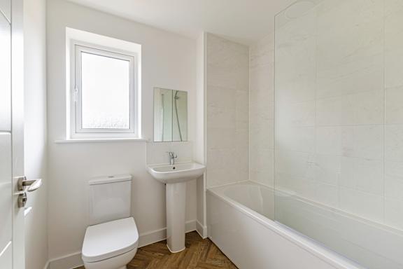 A white bathroom with a toilet, sink, and bathtub.