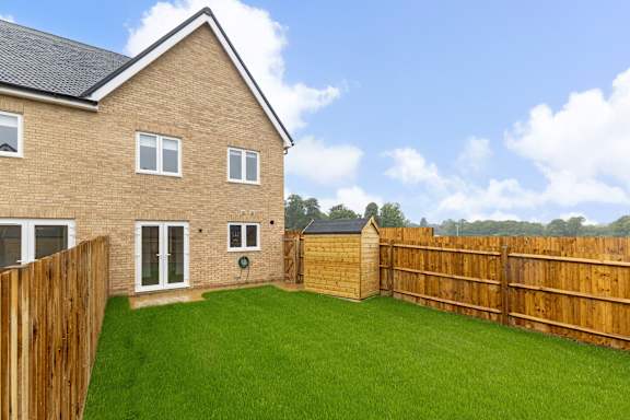 A house with a wooden fence and a green lawn.