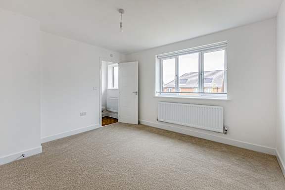 A room with a carpeted floor and a window with a white frame.