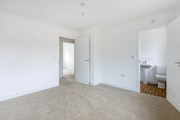 A white room with a carpeted floor and a toilet in the corner.
