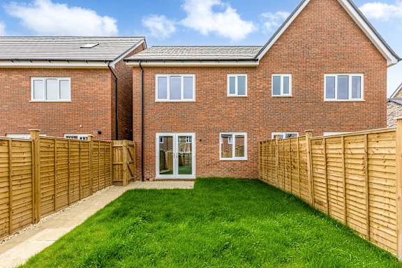 A red brick house with a wooden fence and green grass.