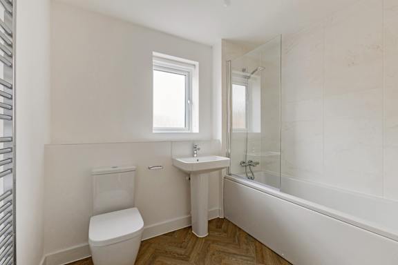 A white bathroom with a toilet, sink, and bathtub.