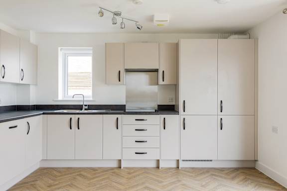 A kitchen with white cabinets and a black countertop.