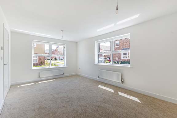 A room with two windows and a carpeted floor.