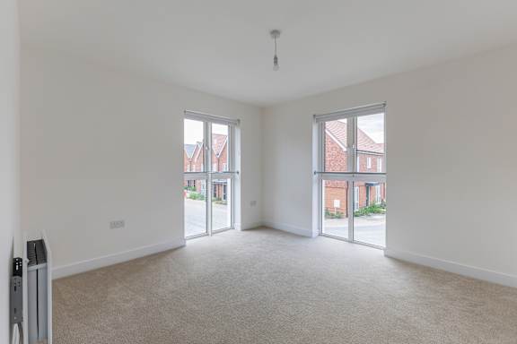 A spacious room with a carpeted floor and white walls.