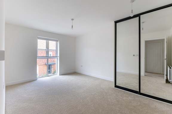 A room with a large mirror on the wall and a window with blinds.