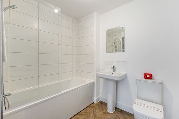 A white bathroom with a tub, sink, and toilet.