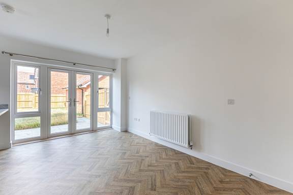 A room with a wooden floor and a white wall with a radiator.