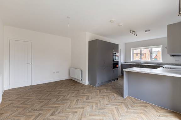 A kitchen with a grey counter top and a wooden floor.