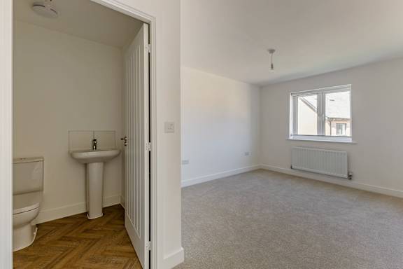 A white bathroom with a toilet, sink, and window.