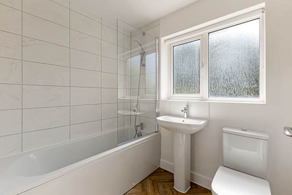 A white bathroom with a tub, sink, and toilet.