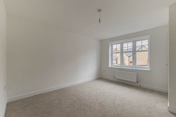 A room with a window and a radiator on the floor.