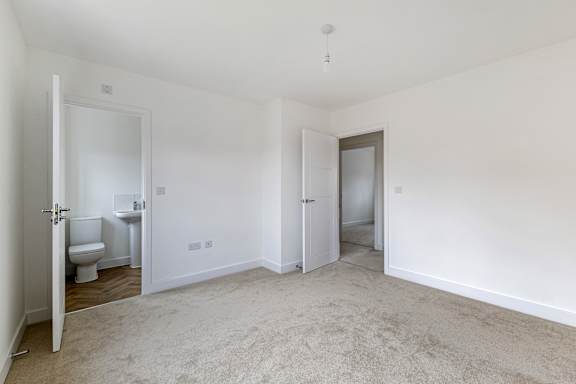 A white room with a carpeted floor and a toilet visible through an open door.