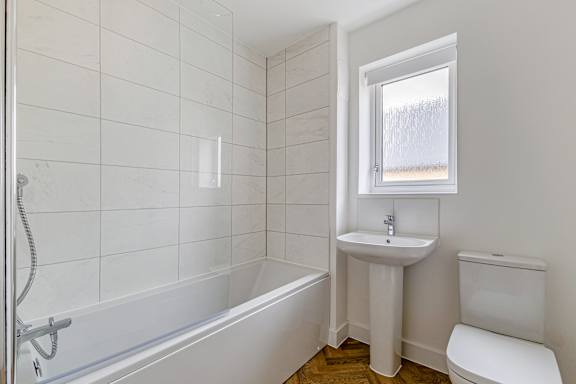 A white bathroom with a tub, sink, and toilet.
