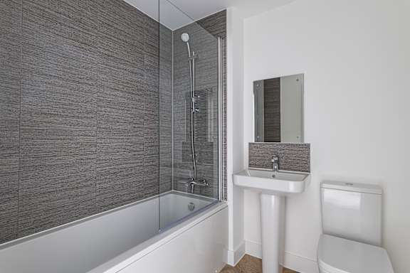 A modern bathroom with a walk-in shower, white sink, and toilet.