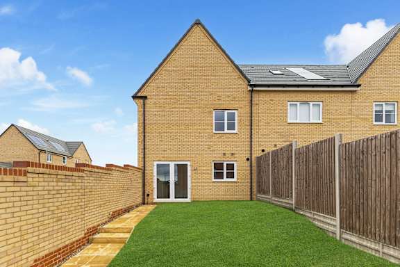 A house with a brown brick exterior and a green lawn.