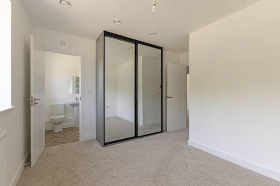 A white bathroom with a toilet, sink, and mirror.