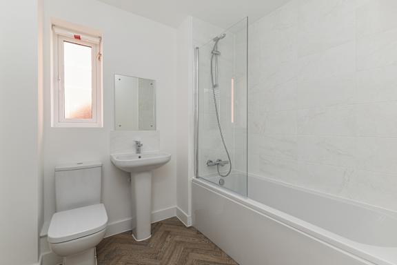 A white bathroom with a toilet, sink, and bathtub.