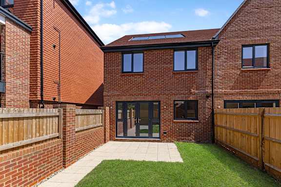 A red brick house with a wooden fence and a green lawn.