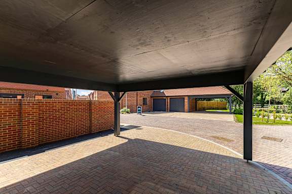 A covered walkway with brick flooring and a metal roof.
