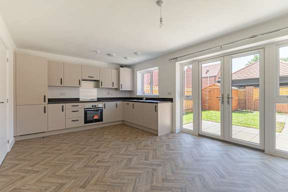 A kitchen with wooden flooring and white walls.