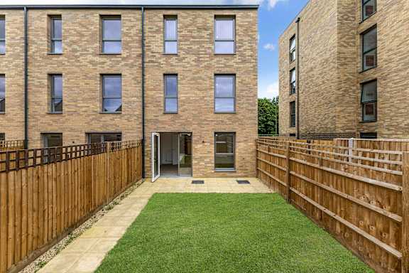 A view of a courtyard with a wooden fence and a grassy area.