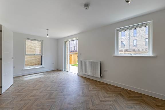 A room with a wooden floor and a window with blinds.