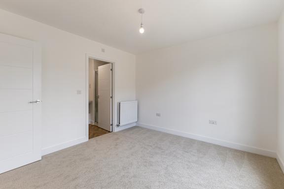 A white room with a carpeted floor and a white door.