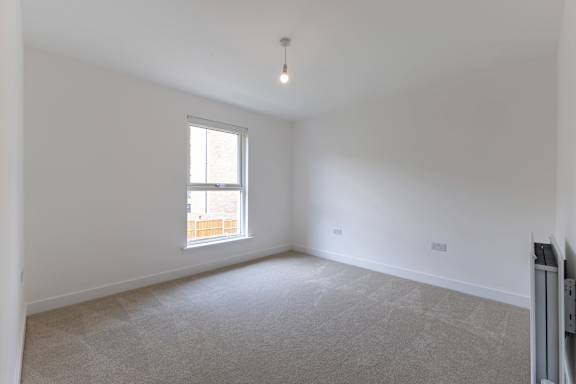 A room with a window and a carpeted floor.