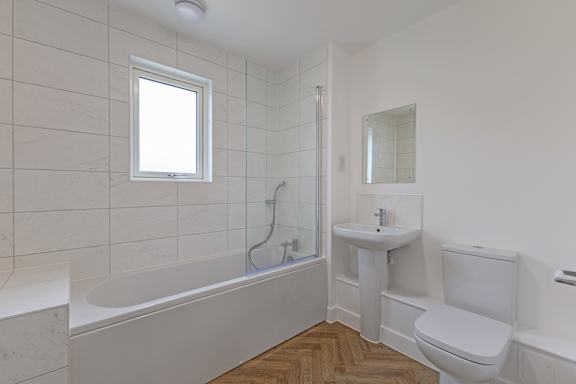 A white bathroom with a tub, sink, and toilet.