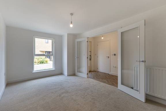 A room with a window, a door, and a carpeted floor.