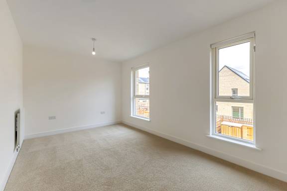 A room with a carpeted floor and two windows.