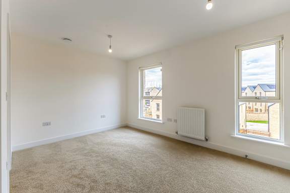 A room with two windows and a radiator on the wall.