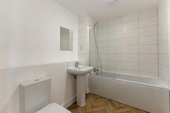 A white bathroom with a toilet, sink, and bathtub.