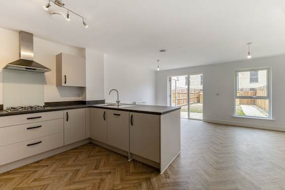 A kitchen with a wooden floor and white walls.