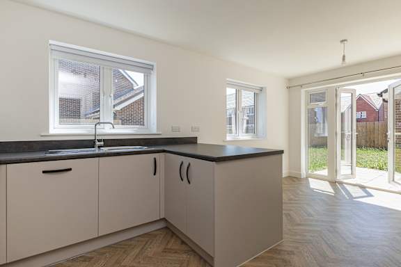 A kitchen with white cabinets and a black countertop.