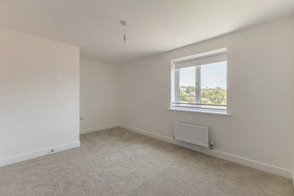 A room with a window and a radiator on the floor.