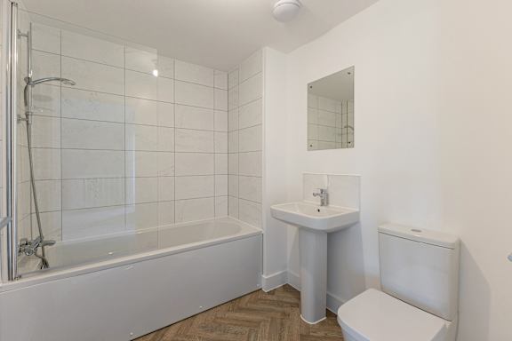 A white bathroom with a tub, sink, and toilet.