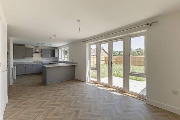 A kitchen with a countertop and a sink is visible through a set of glass doors.