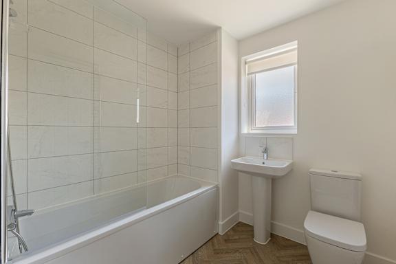 A white bathroom with a tub, sink, and toilet.