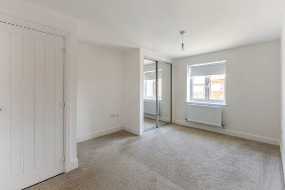 A room with a white door and a carpeted floor.