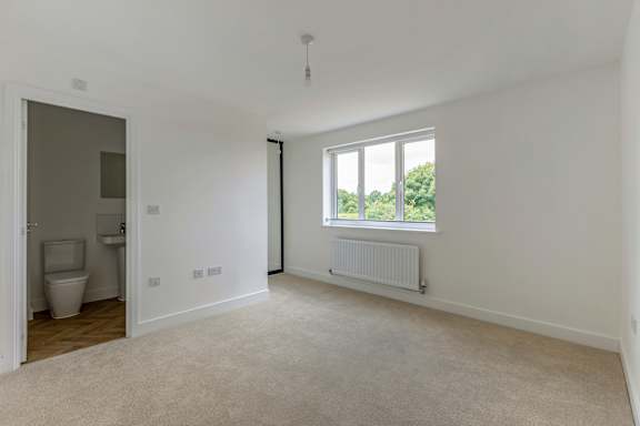 A white room with a toilet and a window.